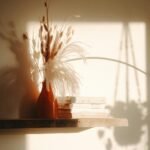 Stillleben eine rote Vase mit Trockenblumen wird beleuchtet durch Licht, dass durch ein Fenster einfällt als Symbol für Entspannung die entsteht, wenn man Körpersignale verstehen lernt und schaut was der Körper mit Müdigkeit, Schlaflosigkeit und innerer Unruhe sagen möchte.